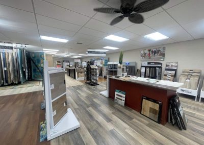 A flooring store interior with wood samples, display racks, and a counter under bright ceiling lights showcases Eastman's Carpets Inc's quality flooring solutions.